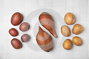 Different types of fresh potatoes on white table, flat lay