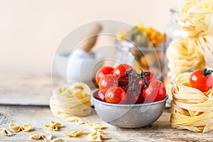 Different types of italian pasta in glass jars on a yellow wooden table. copy space. Selective focus