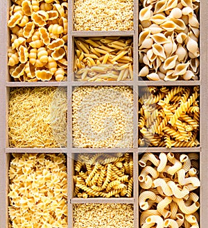 Different types of italian uncooked pasta in wooden box, whole wheat pasta, pasta, spaghetti, noodles, tagliatelle. Top view