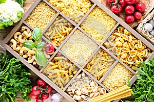 Different types of italian uncooked pasta in wooden box, whole wheat pasta, pasta, spaghetti, noodles, tagliatelle. Top view