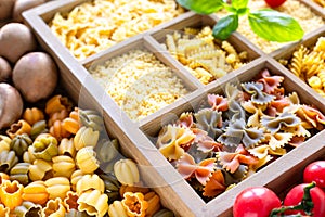Different types of italian uncooked pasta in wooden box, whole wheat pasta, pasta, spaghetti, noodles, tagliatelle. Top view