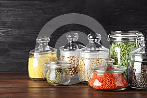 Different types of legumes and cereals in glass jars on table. Organic grains