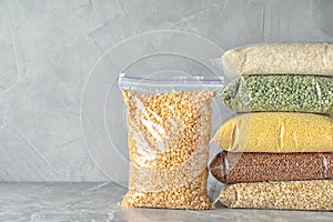 Different types of legumes and cereals on marble table, space for text. Organic grains