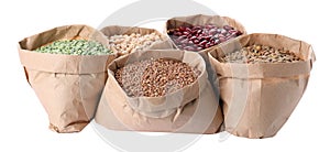 Different types of legumes and cereals in paper bags on background. Organic grains