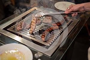 Different types of meat, beef steaks and pork sausages, cooked on a grill
