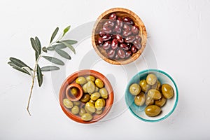 Different types of olives green and black in bowls on white table. Top view, close-up, copy space