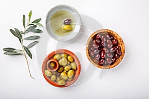 Different types of olives green and black in bowls on white table. Top view, close-up, copy space