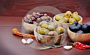 Different types of olives in a wooden bowls