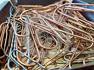 Different types of paperclips in a pile, closeup photo