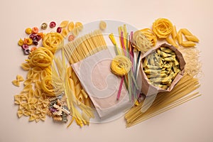 Different types of pasta on beige background, flat lay