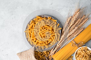 Different types of pasta on a gray concrete background.