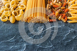 Different types of pasta on a stone background