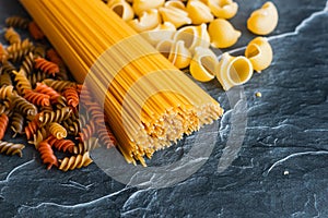 Different types of pasta on a stone background