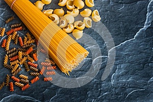 Different types of pasta on a stone background