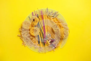 Different types of pasta on yellow background, flat lay