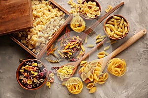 Different types of raw pasta on grey background