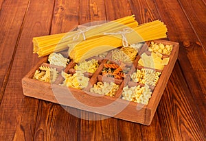 Different types of raw pasta on wood