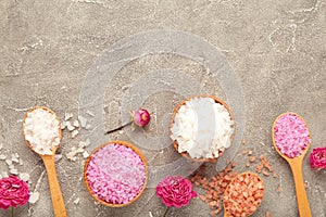 Different types of salt with roses on grey background