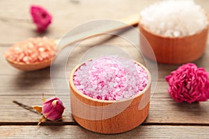 Different types of salt with roses on grey background