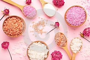 Different types of salt with roses on pink background