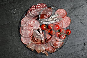 Different types of sausages with tomatoes served on black table, flat lay