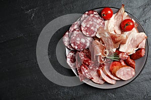 Different types of sausages with tomatoes served on black table. Space for text