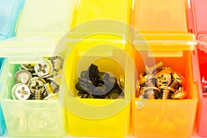 Different types of screws in small colored plastic containers. V