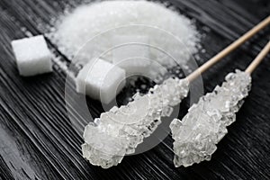 Different types of sugar on black wooden table, closeup