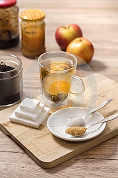 Different types of sugar lie on a wooden board. Tea brewed in a glass.