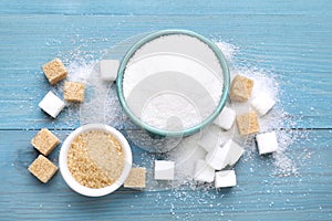 Different types of sugar on light blue wooden table, flat lay