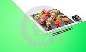 Different types of sushi are served on a black plate. Colorful sunny background. Sushi menu for japanese food. Japanese sushi set