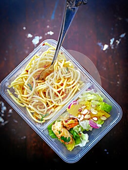 Different types of takeaway food in microwavable containers on a wooden background.