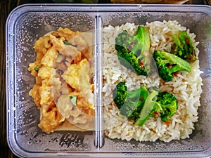 Different types of takeaway food in microwavable containers on a wooden background.