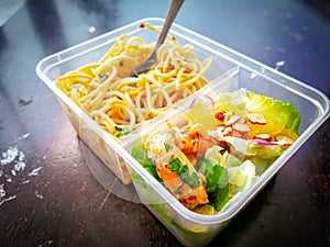 Different types of takeaway food in microwavable containers on a wooden background.
