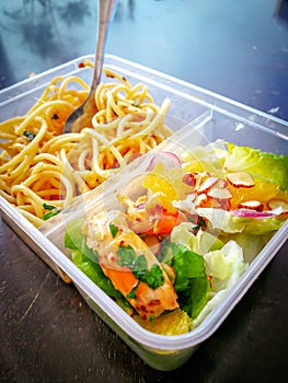 Different types of takeaway food in microwavable containers on a wooden background.