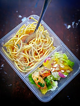 Different types of takeaway food in microwavable containers on a wooden background.