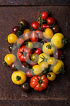 Different types of tomatoes on rusty background