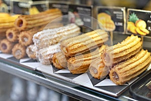 Different types of traditional sweet spanish dessert churros with filling on the market or bakery showcase. Hot baked