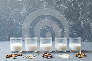 Different types of vegan non-dairy milk in glasses on wooden background with copy space