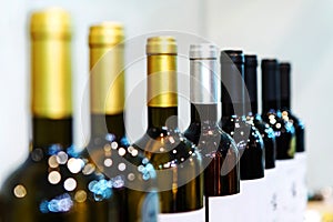 Different types of wine bottles stand on a white background. Trade in alcoholic beverages in the store. Selective focus. Cropped