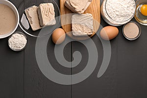 Different types of yeast, eggs and flour on grey wooden table, flat lay. Space for text