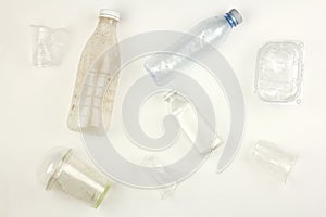 Different used dirty plastic disposable tableware and garbage, bottles cups and containers, white background, pollution