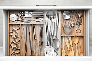 Different utensils in open desk drawer