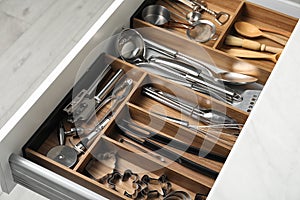 Different utensils in open desk drawer