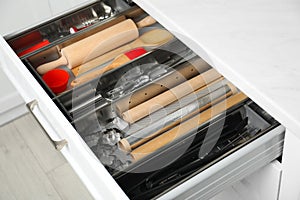 Different utensils in open desk drawer