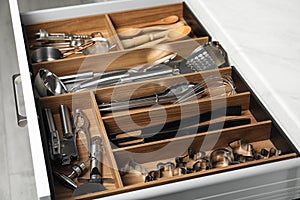 Different utensils in open desk drawer