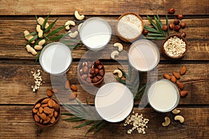 Different vegan milks and ingredients on wooden table, flat lay