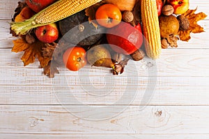 Different vegetables pumpkins, apples, pears, nuts, corn, tomatoes, dry yellow leaves on white wooden background. Autumn Harvest