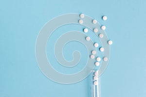 Different white pills and a plastic container on a blue background.