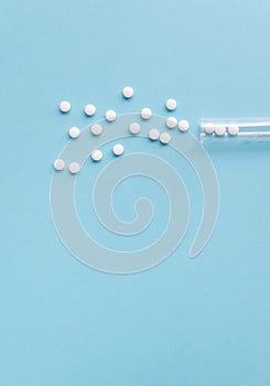Different white pills and a plastic container on a blue background.